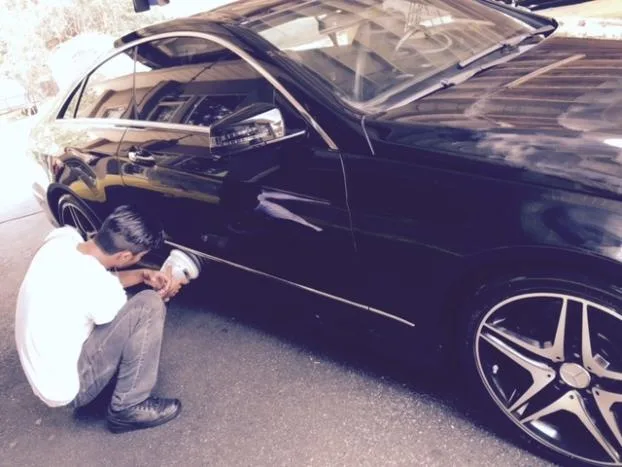 Staff member hand-detailing the wheel and trim of a Mercedes-Benz