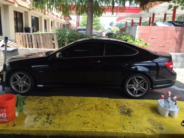 Black Mercedes-Benz C-Class parked at the wash bay with cleaning supplies